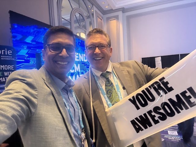Exhibit floor selfie with a You're Awesome sign, Becker's HIT + RCM 2026, photo 7 of 8